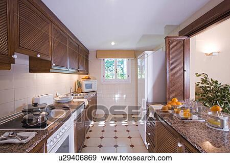 Apartment kitchen with dark wood cupboards and cream and brown tiles on the floor View Large Photo Image Stock Photo - Apartment kitchen with dark wood cupboards and cream and brown tiles on the floor. Fotosearch