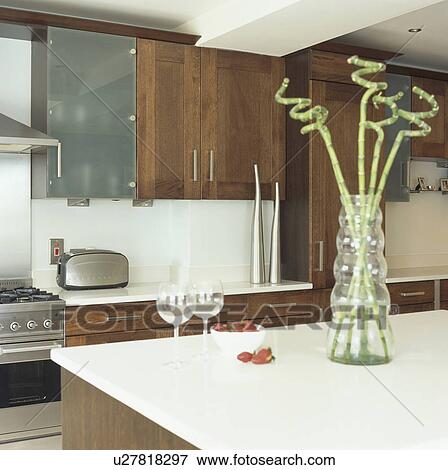 Bamboo stems in glass vase on white worktop in modern kitchen with dark wood cupboards View Large Photo Image Stock Photo - Bamboo stems in glass vase on white worktop in modern kitchen with dark wood cupboards . Fotosearch