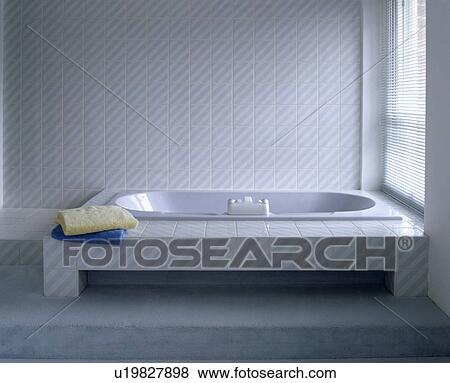 Stock Photo - Bath with tiled surround in modern tiled bathroom. Fotosearch