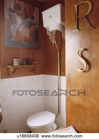 Stock Photo - Bathroom with brass initials on paint effect sponged wall beside white toilet. Fotosearch