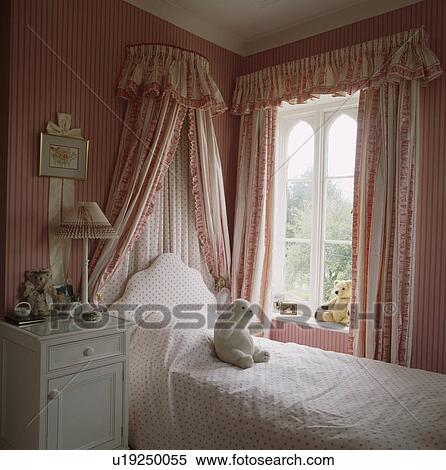 Bed With Coronet And Drapes Beside Window In Child S Bedroom With Pink Striped Wallpaper And Pink Curtains Stock Photography