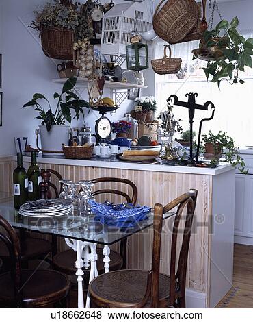 Stock Photo - Bentwood chairs and glass-topped table in front of peninsular unit in small kitchen. Fotosearch