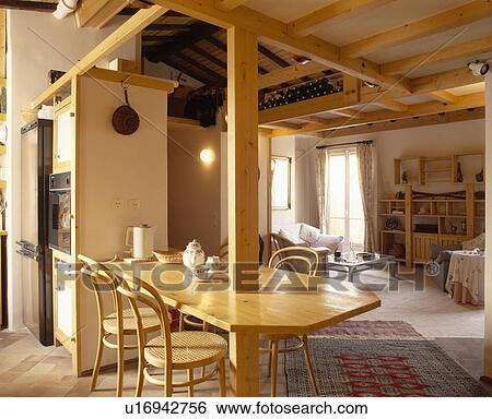 Stock Photograph - Bentwood chairs at table built into upright beam in eighties country dining and living room. Fotosearch