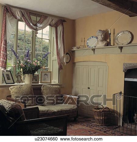 Bergere sofa below window with draped fabric in traditional living room View Large Photo Image Stock Image - Bergere sofa below window with draped fabric in traditional living room. Fotosearch