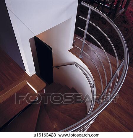 Stock Photo - Birdseye view down wooden steps of spiral staircase surrounded with metal rail. Fotosearch