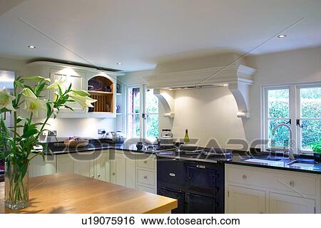 Black Aga between windows in white country kitchen with recessed lighting View Large Photo Image Stock Photograph - Black Aga between windows in white country kitchen with recessed lighting. Fotosearch