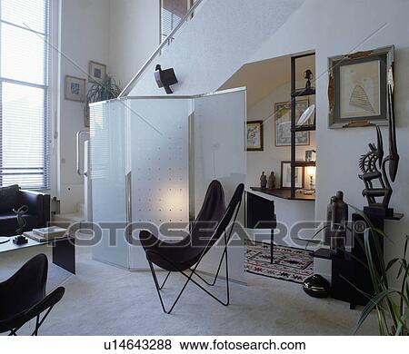 Black butterfly chair in front of glass screen in modern white living room View Large Photo Image Stock Photo - Black butterfly chair in front of glass screen in modern white living room. Fotosearch