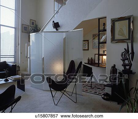 Black butterfly chair in front of glass screen in modern white living room View Large Photo Image Stock Photo - Black butterfly chair in front of glass screen in modern white living room. Fotosearch