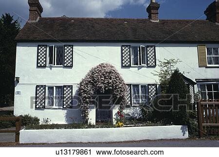 Black fretwork shutters on white cottage with pink clematis above front door View Large Photo Image Stock Image - Black fretwork shutters on white cottage with pink clematis above front door. Fotosearch