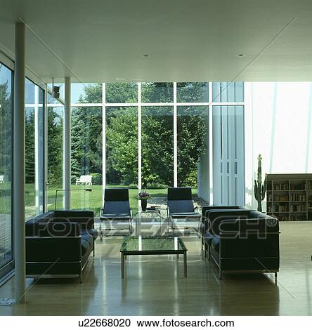 Stock Image - Black leather and chrome sofas in modern living room. Fotosearch