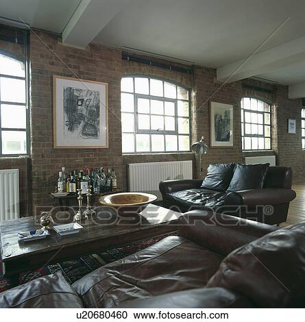 Stock Image - Black leather sofas and wooden coffee table in loft conversion living room. Fotosearch