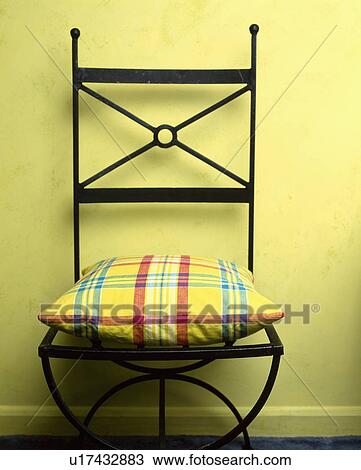 Black metal chair with cushion against yellow painted wall. View Large Photo Image Stock Image - Black metal chair with cushion against yellow painted wall.. Fotosearch