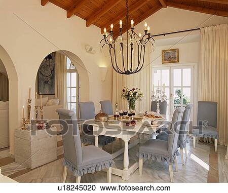 Black Metal Chandelier Above White Table With Blue Upholstered