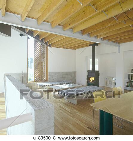 Black stove and striped daybeds in modern openplan living and diningroom with wooden ceiling View Large Photo Image Stock Photo - Black stove and striped daybeds in modern openplan living and diningroom with wooden ceiling. Fotosearch
