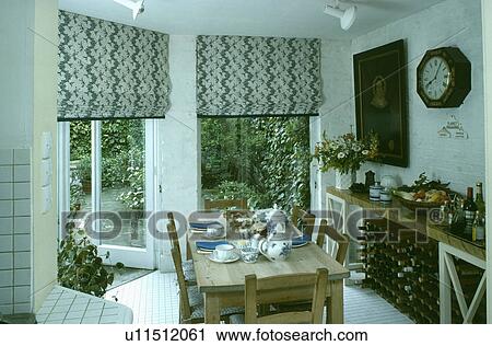 Black+white patterned blinds on patio doors in small white dining room with pine table and chairs View Large Photo Image Stock Image - Black+white patterned blinds on patio doors in small white dining room with pine table and chairs. Fotosearch