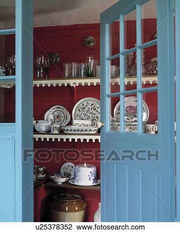 Stock Image - Blue and red pantry through open door.. Fotosearch