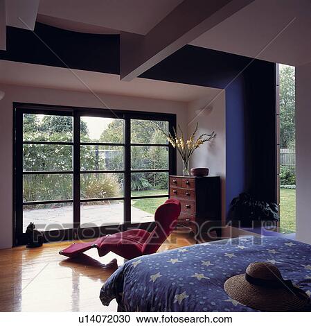 Stock Image - Blue and white architectural bedroom overlooking garden.. Fotosearch