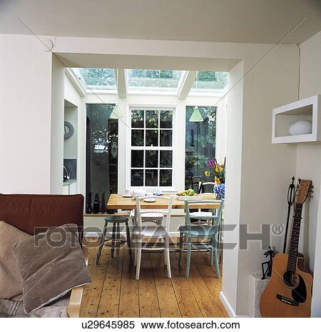 Stock Photography - Blue and white chairs and wooden table in white dining room extension with wooden flooring. Fotosearch