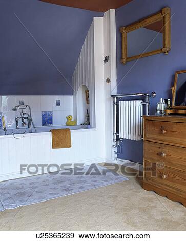 Stock Photo - Blue and white painted bathroom with radiator and pine mirror and chest.. Fotosearch