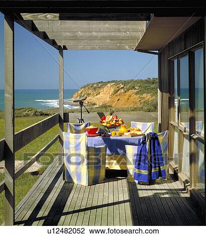 Blue and yellow checked chairs and table laid for lunch on wooden veranda of traditional house in Australia with a view of the sea View Large Photo Image Stock Image - Blue and yellow checked chairs and table laid for lunch on wooden veranda of traditional house in Australia with a view of the sea. Fotosearch