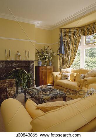 Stock Image Of Blue And Yellow Swagged Curtains In Pastel Blue And Yellow Swagged Curtains In Pastel Living Room With Pale Sofas
