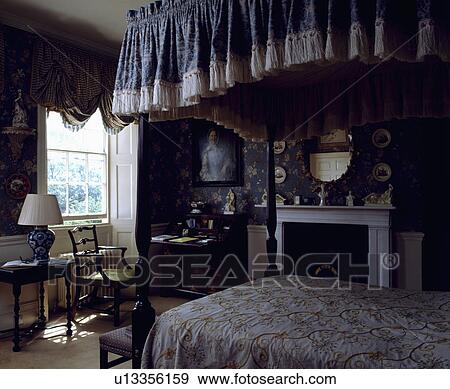 Blue floral pelmet on four-poster bed in traditional country bedroom with blue floral wallpaper View Large Photo Image Stock Photo - Blue floral pelmet on four-poster bed in traditional country bedroom with blue floral wallpaper. Fotosearch