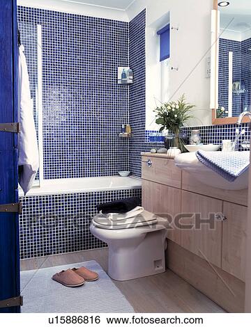 Stock Photograph - Blue mosaic tiles surround the bath and shower in this modern bathroom. Fotosearch