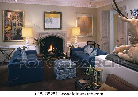 Stock Image - Blue sofas and lighted lamps in traditional living room. Fotosearch