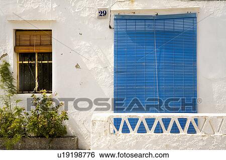 Stock Photograph - Blue split cane blind on window with white balcony on traditional whitewashed Spanish house. Fotosearch