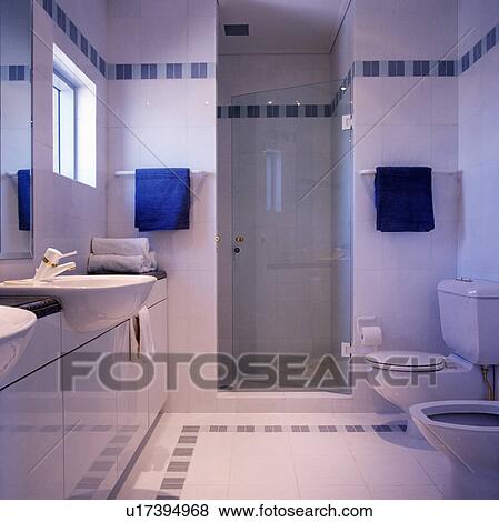 Blue towels on either side of glass door to shower in modern white bathroom with blue tile detail View Large Photo Image Stock Photo - Blue towels on either side of glass door to shower in modern white bathroom with blue tile detail. Fotosearch