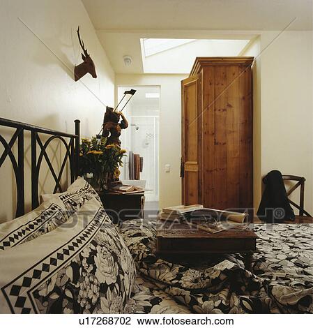 Stock Image - Books on bed with black+white pillows and matching duvet in modern white bedroom . Fotosearch