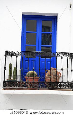Cacti In Pots On Wrought Iron Balcony In Front Of Bright Blue