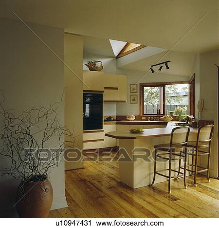 Cane and wood stools at breakfast bar in large modern kitchen extension with wooden flooring View Large Photo Image Stock Image - Cane and wood stools at breakfast bar in large modern kitchen extension with wooden flooring. Fotosearch
