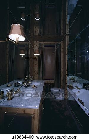 Cantilevered wall-light above basins in marble-topped vanity unit in traditional panelled bathroom View Large Photo Image Stock Image - Cantilevered wall-light above basins in marble-topped vanity unit in traditional panelled bathroom. Fotosearch