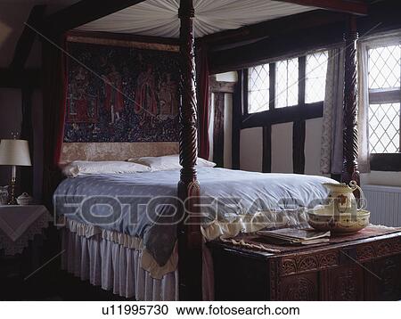 Stock Image - Carved antique bed in country house bedroom. Fotosearch