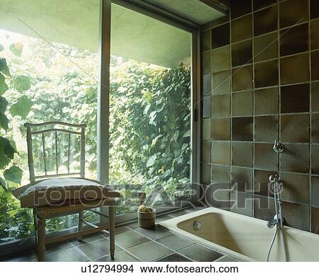 Chair beside patio doors in tiled bathroom with sunken bath View Large Photo Image Picture - Chair beside patio doors in tiled bathroom with sunken bath. Fotosearch