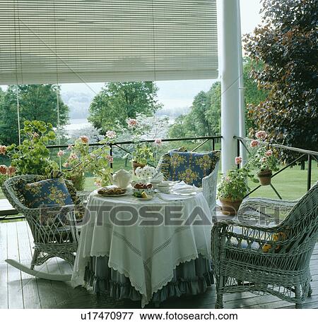 Stock Photo - Chairs and table with cloth on veranda in country garden in summer. Fotosearch