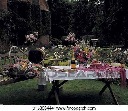 Picture - Champagne on table with white cloth in large country garden in summer. Fotosearch