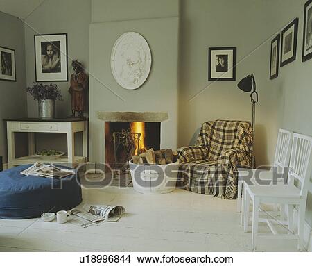 Checked throw on armchair beside fireplace in traaditional living room with white painted floorboards View Large Photo Image Picture - Checked throw on armchair beside fireplace in traaditional living room with white painted floorboards. Fotosearch