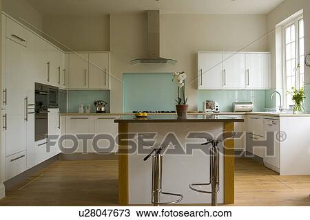 Chrome and perspex stools at breakfast bar in modern white kitchen extension with wooden flooring View Large Photo Image Stock Image - Chrome and perspex stools at breakfast bar in modern white kitchen extension with wooden flooring. Fotosearch
