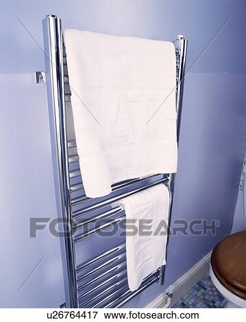 Stock Photo - Chrome towel rail with white towels fixed on blue painted wall. Fotosearch