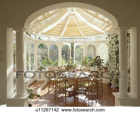 Classical pillars in conservatory dining room with split cane ceiling blinds and circular table with cane chairs View Large Photo Image Stock Image - Classical pillars in conservatory dining room with split cane ceiling blinds and circular table with cane chairs. Fotosearch