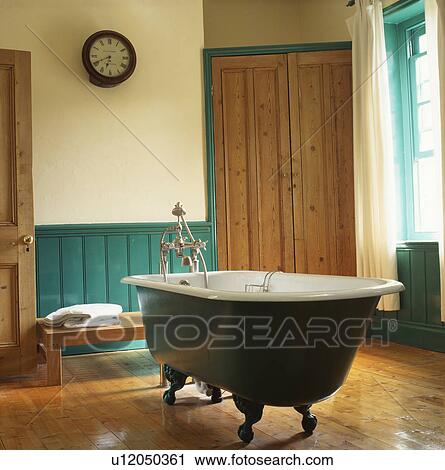 Clawfoot bath in centre of cream bathroom with turquoise dado panelling and wooden flooring View Large Photo Image Stock Image - Clawfoot bath in centre of cream bathroom with turquoise dado panelling and wooden flooring. Fotosearch
