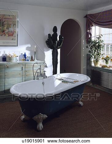 Clawfoot bath with central taps in the centre on white bathroom with tall artificial cactus and seagrass carpet View Large Photo Image Stock Image - Clawfoot bath with central taps in the centre on white bathroom with tall artificial cactus and seagrass carpet. Fotosearch