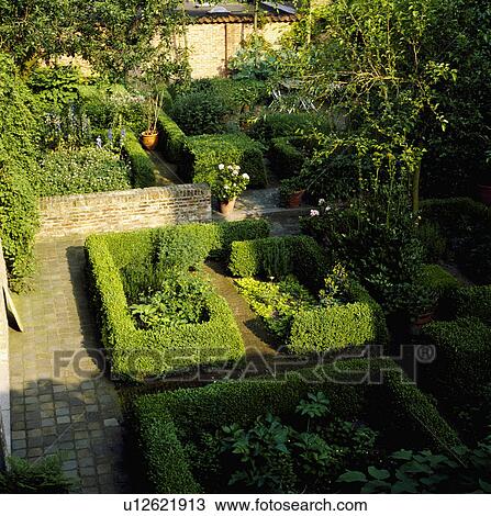 Stock Image - Clipped hedges in formal country garden in summer. Fotosearch