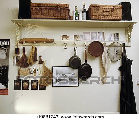 Stock Photo - Close-up of baskets on shelf above pegrail with brushes and pans. Fotosearch