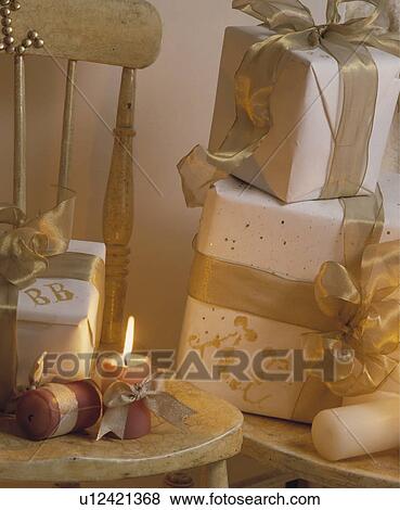 Stock Photo - Close-up of Christmas presents wrapped with white paper and gold ribbon. Fotosearch
