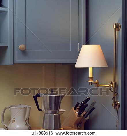 Close-up of chrome coffeepot and knife block below lighted wall lamp and blue kitchen cupboard View Large Photo Image Stock Photograph - Close-up of chrome coffeepot and knife block below lighted wall lamp and blue kitchen cupboard . Fotosearch