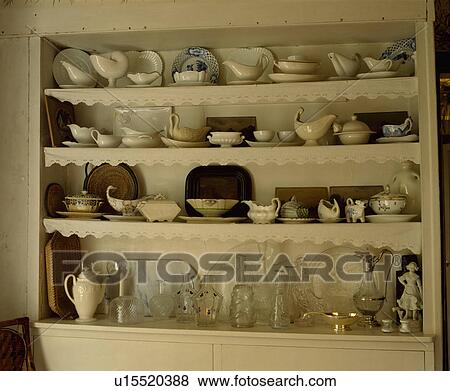 Stock Photo - Close-up of collection of cream china on shelves with lace trimming. Fotosearch