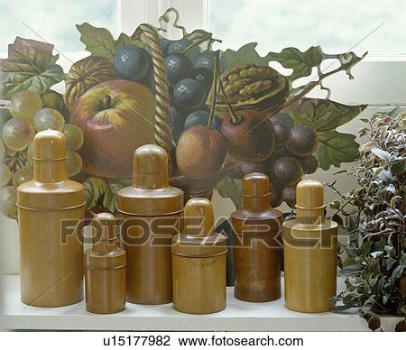 Stock Image - Close-up of collection of Treen bottles in front of picture of fruit. Fotosearch
